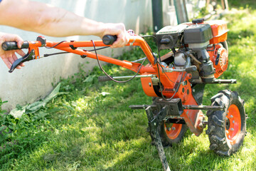 Man Farmer plows the land with a cultivator. Agricultural machinery: cultivator for tillage in the garden,motor cultivator