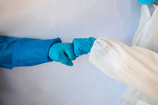 Hands In Medical Gloves Greeting Each Other With Fist Bump On White Background.