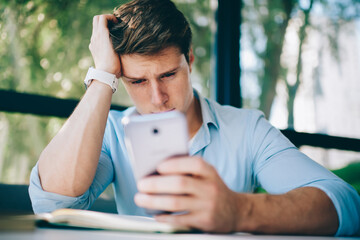 Fototapeta premium Thoughtful hipster blogger updating profile on telephone