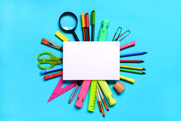 Group of School or office supplies around a notepad on light blue background. Space for text.