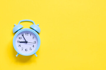 Blue alarm clock on yellow background