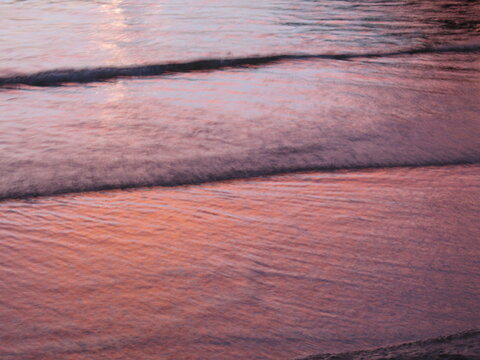 Abstract landscape reflection of a pink sunset on waves on Chuao beach