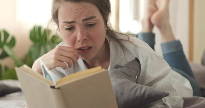 Sensitive woman crying while reading book at home
