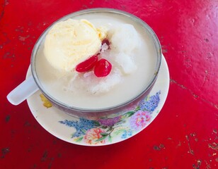 Top view Special iced cendol or Malaysian called cendol pulut special with sticky rice,cendol,corn,peanuts,red beans and vanila ice cream on red table