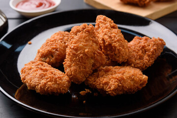 Fried breaded chicken wings on wooden table. Close up 