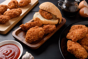 Fried breaded chicken wings with hamburger bread on wooden table.