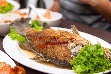 Dinner Fried fish with vegetables on a white plate topped with fish sauce