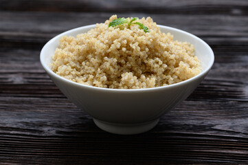 Bowl of boiled quinoa on wood background