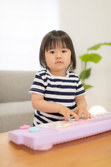 おもちゃのキーボードを弾いて遊ぶ3歳の女の子