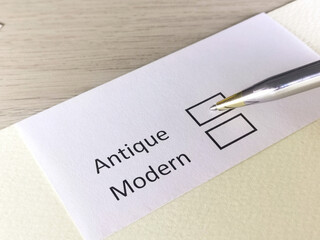 One person is answering question on a piece of paper. The person is thinking to be modern or antique.