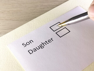 One person is answering question on a piece of paper. The person is thinking to choose son or daughter.