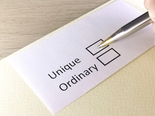 One person is answering question on a piece of paper. The person is thinking to be unique or ordinary.