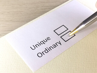 One person is answering question on a piece of paper. The person is thinking to be unique or ordinary.