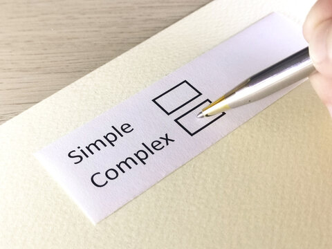 One person is answering question on a piece of paper. The person is thinking to be simple or complex.