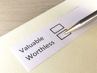 One person is answering question on a piece of paper. The person is thinking to choose valuable or worthless.