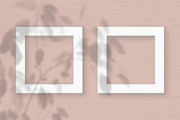 Fototapeta premium Two square sheet of white textured paper on the peach wall background. Mockup with an overlay of plant shadows. Natural light casts shadows from the leaves of an exotic plant. Flat lay, top view
