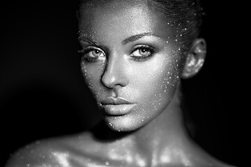 Fashion model woman in bright sparkles and lights posing in studio. Portrait of beautiful sexy...