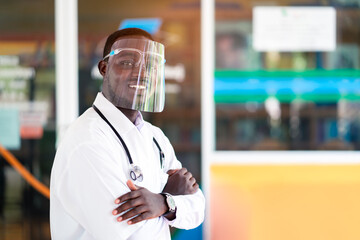 African doctor wear face shield and holding stethoscope with kind and smiling