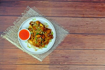 Crispy fried mussels pancake on wooden table with space on the right.