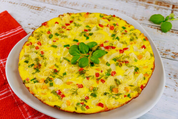 Homemade omelette with vegetables on white plate.
