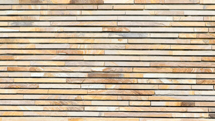Decorative texture of a beautiful wall with rectangular parts made of multi-colored artificial stone. Collage of narrow granite blocks. Exterior finish with stone. Background from natural material.