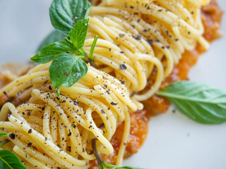 Spaghetti with tomato sauce,Ingredients Tomatoes,Minced pork,Garlic,Pepper,Basil,Is Italian food Placed on a white plate