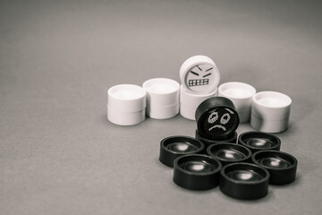 Faces on checkers in the form of facial expressions that reflect emotions. The concept of racism, misunderstanding, a barrier in relations, the denial of society. Barriers between people.