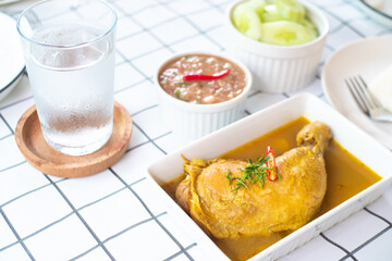 Thai style traditional yummy delicious food hot and spicy chicken curry on the table with glass of water chili paste and vegetable.