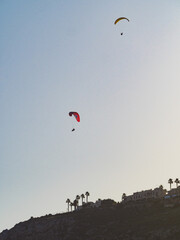 Paragliders flying in blue sky.