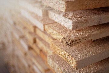Stack of natural rough wooden boards close-up. Storage of wood in a carpenter's workshop or at a sawmill