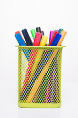 Drawing supplies concept. Photo of colorful markers in yellow pencil cup isolated on white background