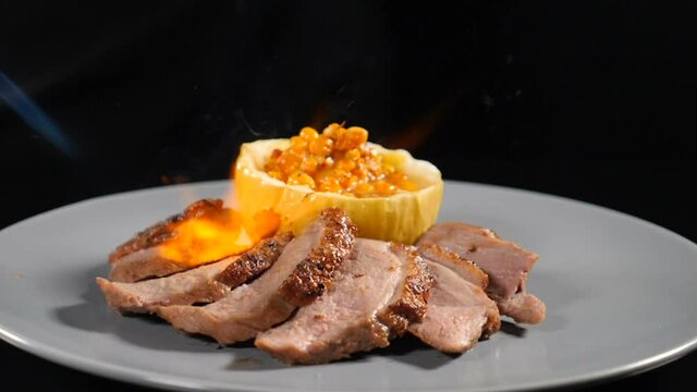 Food footage in slow motion. Fire out of gas burner in chef hands while cooking. Dish with sliced meat and stuffed baked pumpkin served on white plate. Full hd