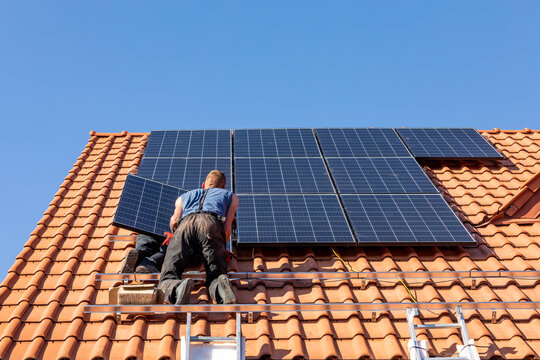 Workers installing solar electric panels on a house roof in  Ochojno. Poland