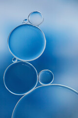 Macro of oil and water bubbles creating a scientific image of cell and cell membrane in blue in a vertical format.