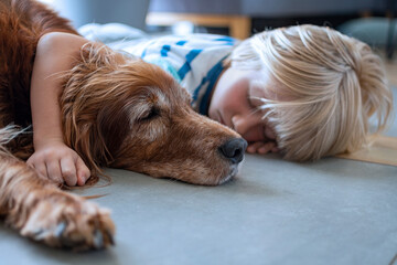 Young boy sleeps on the floor with big, old dog