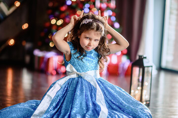 Cute little girl laying on flor with bright christmas garland in her hair.