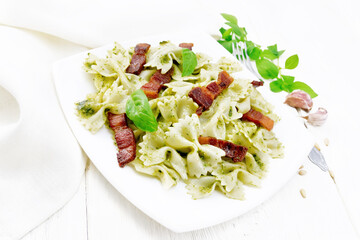 Farfalle with pesto and bacon in plate on board