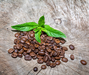 Obraz premium Coffee beans and mint leaves on a wooden surface.