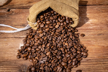 Coffee beans spilled from a bag on a wooden surface