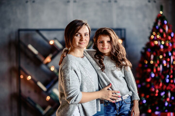 Mother and Child Hug in Front of a Christmas Tree.