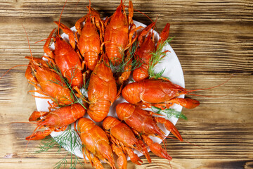 Boiled crayfish in plate on wooden table. Top view