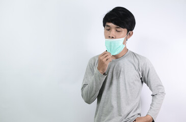 Asian man in a gray t-shirt and wearing a medical mask isolated on a white background