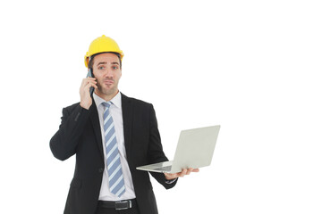 Handsome and smart engineer in black suit Wearing a yellow safety engineerking hat with hand holding labtop and call in mobile for work isolated on yellow background. Copy Space