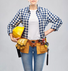 repair, construction and building concept - woman or builder with helmet and working tools on belt over grey background