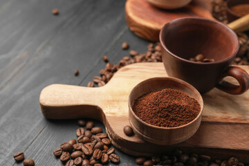 Cup and bowl with coffee beans and powder on wooden background