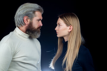 Modern man posing with his woman on black background.