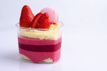 Heart shaped red velvet cake decorated with strawberry and macaron on pink background