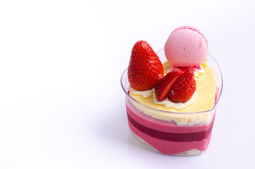 Heart shaped red velvet cake decorated with strawberry and macaron on pink background