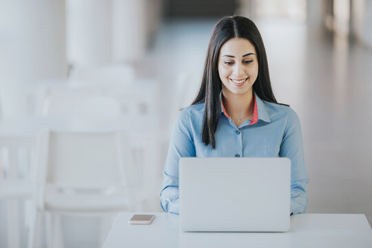 Happy new intern sitting at a desk, preparing a presentation for a meeting on a laptop