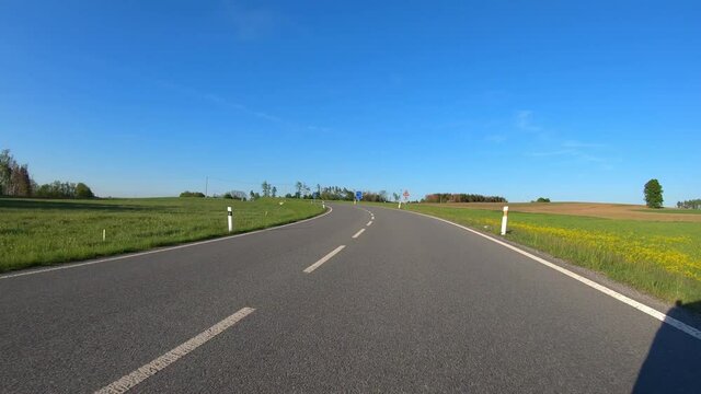 car drive in spring countryside road, sunny landscape with field and meadow. Europe travel concept